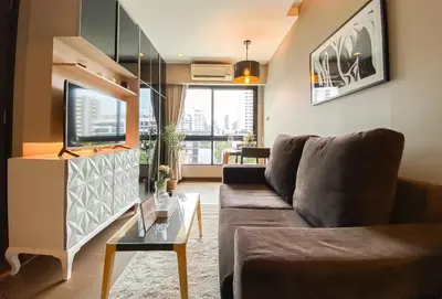 a living room with a couch and a table at Tropical Haven 1BR - Ultra Fast WiFi - Thong Lo in Bangkok