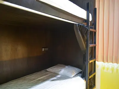 a bunk bed with a pillow on the bottom bunk at BOB Hostel सुख सदन ひだまり庵 파란달여관 in Bangkok