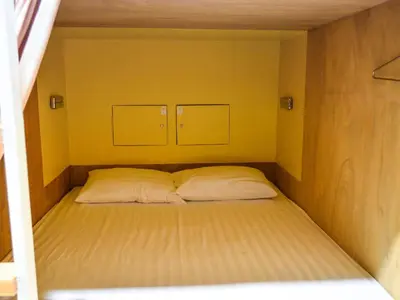 a bed in a small room with two pillows at BOB Hostel सुख सदन ひだまり庵 파란달여관 in Bangkok