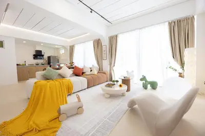 a white living room with a white couch and a yellow blanket at Ratchada Retreat Boutique Suites in Bangkok