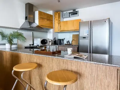 a kitchen with a stainless steel refrigerator and two stools at Downtown View 65 SQM - Ultra Fast Wifi - Sathorn in Bangkok