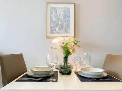 a dining room table with a vase of flowers and glasses at Stylish Modern 1BR - BTS Phrom Phong - Ultra Fast WiFi in Bangkok
