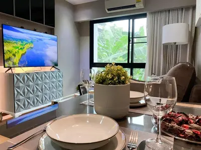 a dining room with a table with glasses and a tv at Tropical Paradise 1BR - Ultra Fast Wifi - Thong Lo in Bangkok