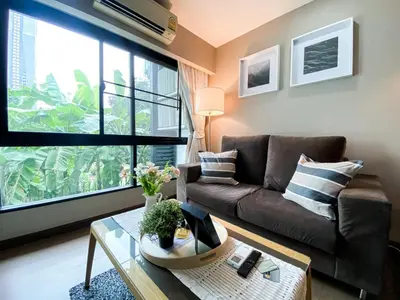 a living room with a couch and a large window at Tropical Paradise 1BR - Ultra Fast Wifi - Thong Lo in Bangkok
