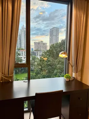 a desk and a window with a view of a city at Cozy Spacious 1BR 3pax GardenView, 700m BTS ThongLo, Samitivej, SKV49, Fast wifi in Bangkok