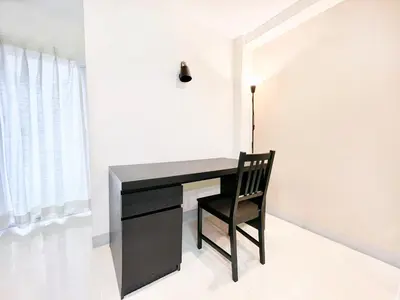 a black desk with a chair next to a window at Grand Residence in Bangkok