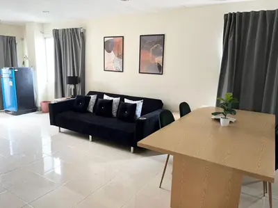 a living room with a black couch and a table at Grand Residence in Bangkok