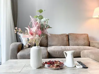 a living room with a couch and a table with a vase at 2Br Modern Comfort at Vibrant Asok BTS Station in Bangkok
