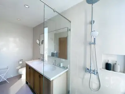 a white bathroom with a sink and a shower at The Grand Penthouse 2BR Ultra Fast WiFi Sukhumvit in Bangkok