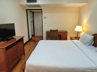 a bedroom with a bed and a flat screen tv at Rent Omni Tower Apartments Nana Bangkok - Prime Sukhumvit location in Bangkok
