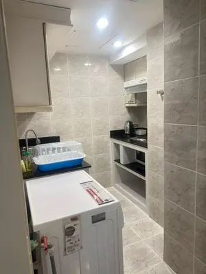 a small kitchen with a counter and a refrigerator at Rent Omni Tower Apartments Nana Bangkok - Prime Sukhumvit location in Bangkok