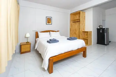 a bedroom with a bed and a refrigerator in it at Tom Guest House ทอมส์ เกสต์เฮ้าส์ in Thung Maha Mek