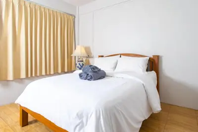 a bedroom with a white bed with a blue towel on it at Tom Guest House ทอมส์ เกสต์เฮ้าส์ in Thung Maha Mek