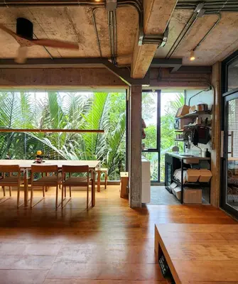 a dining room with a table and a large window at Hiddenwoods in Bang Chak