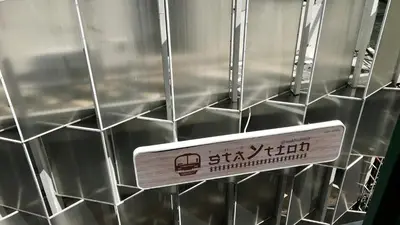 a sign is hanging on a wall with silver tiles at The Staytion Hotel at Sukhumvit in Amphoe Phra Khanong