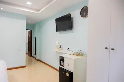 a living room with a clock and a tv on the wall at Cozy Stay Inn in Bang Kapi