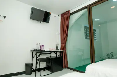 a bedroom with a bed and a desk with a television at The Hostel Era in Bangkok