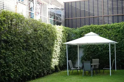 a table and chairs under an umbrella next to a hedge at Sukhumvit 16 Townhouses, InHome Luxury Residences in Bangkok
