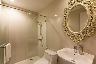 a bathroom with a shower and a sink and a mirror at Sukhumvit 16 Townhouses, InHome Luxury Residences in Bangkok