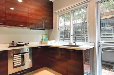 a kitchen with wooden cabinets and a large window at Sukhumvit 16 Townhouses, InHome Luxury Residences in Bangkok