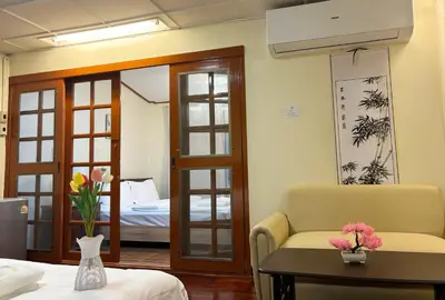 a room with a bed and a table with flowers on it at Apamet Hotel Sukhumvit 55 in Khlong Toei