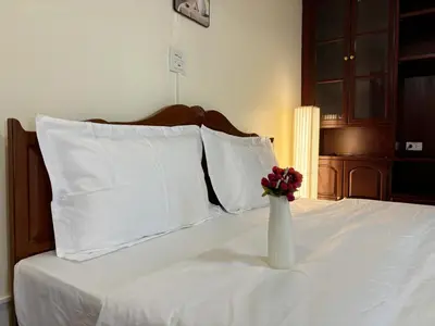 a white vase with a flower in it on a bed at Apamet Hotel Sukhumvit 55 in Khlong Toei
