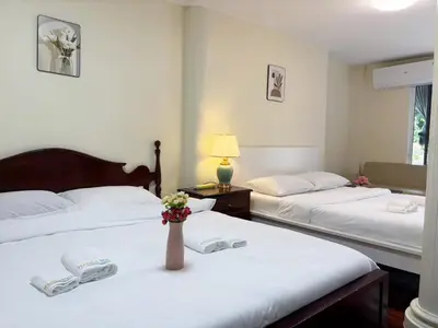 two beds in a hotel room with a vase of flowers at Apamet Hotel Sukhumvit 55 in Khlong Toei