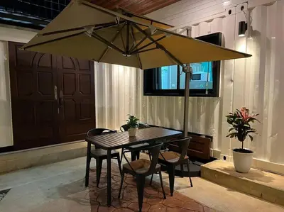 a table and chairs under a large umbrella at \u6d6a\u6f2b\u82b1\u56ed\u7684\u4e24\u5367\u6c11\u5bbf \u72ec\u7acb\u5ead\u9662 \u8fd1mrt 3 in Bang O