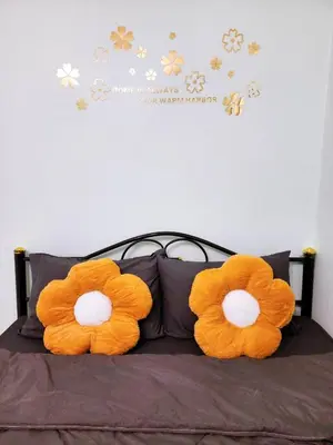 two orange pillows on a bed with flowers on the wall at 807-STP Homely room Free Wi-Fi and Near BTS line in Ban Yang