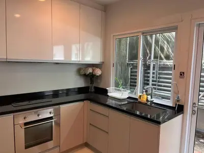a kitchen with white cabinets and a sink and a window at 3BR Sukhumvit Townhouse, close to Emsphere and BTS MRT in Bangkok