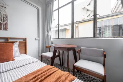 a bedroom with a bed and a table and a window at Sorrento Bangkok Old Town MRT Samyot in Bangkok
