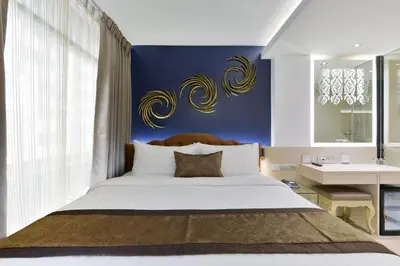 a bedroom with a large bed with a blue wall at Syama Mansion Phromphong in Bangkok