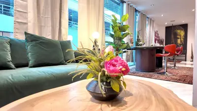 a living room with a couch and a vase with flowers on a table at Syama Mansion Phromphong in Bangkok