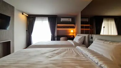 a hotel room with two beds and a window at We Hotel in Ban Bang Toei (1)