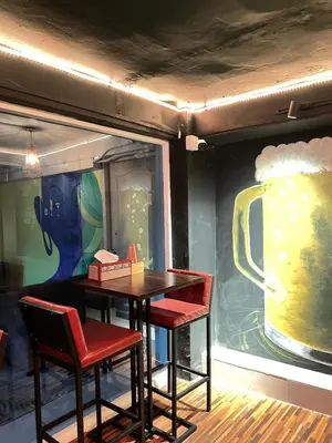 a table and two chairs in a room with a beer mural at Lemon Tree Hostel Khaosan in Bangkok