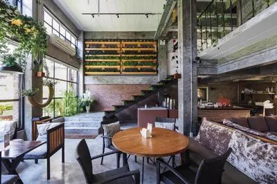 a restaurant with a table and chairs and a staircase at Vm1 Hostel in Bangkok