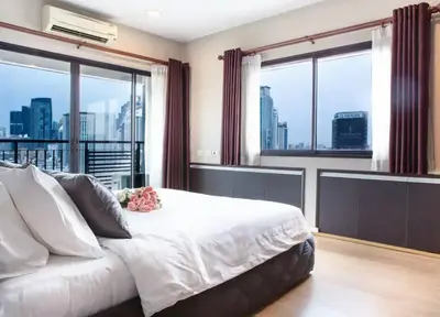 a bedroom with a large bed and large windows at Central 2BR 3 min walk from BTS Ploen Chit in Makkasan