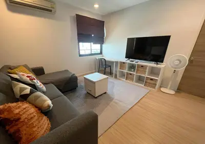 a living room with a couch and a flat screen tv at Central 2BR 3 min walk from BTS Ploen Chit in Makkasan
