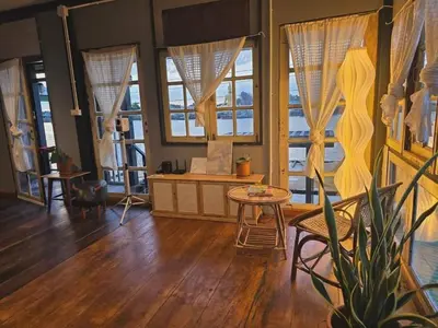 a living room with a table and some windows at เฉื่อย โฮมสเตย์ in Nonthaburi