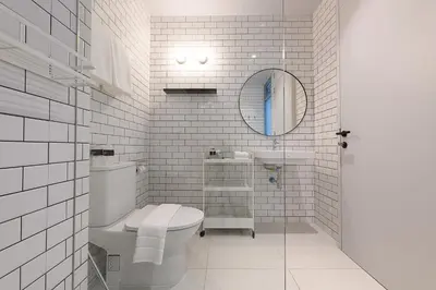 a white bathroom with a toilet and a sink at Mowa Bangkok in Bangkok