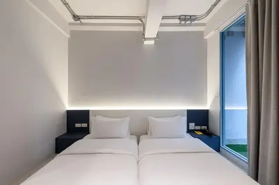 a bedroom with two beds and a window at Mowa Bangkok in Bangkok