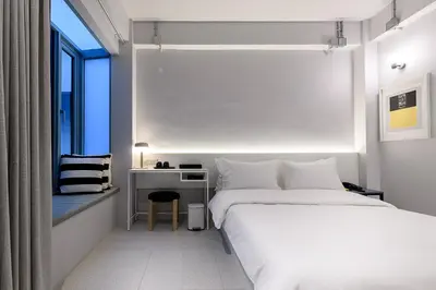 a bedroom with a bed and a desk and a window at Mowa Bangkok in Bangkok