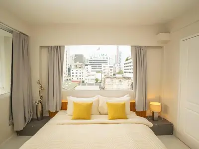 a bedroom with a bed with yellow pillows and a window at Cozy 2-bedroom apartment in Silom city center - 6A in Bang Rak