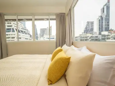 a bedroom with a bed with white pillows and a window at Cozy 2-bedroom apartment in Silom city center - 6A in Bang Rak