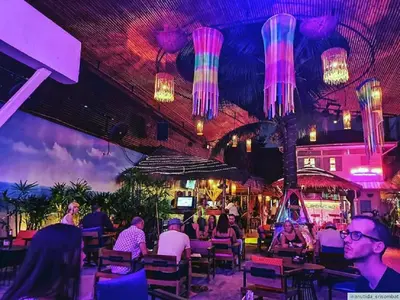 a group of people sitting at a restaurant with lights at XX GO INN Khaosan road The Grand Palace โกอินน์ ถนนข้าวสาร กรุงเทพมหานคร in Bangkok