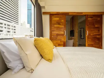a bedroom with a white bed with a yellow pillow at 2 Bedroom apartment at Silom with city center view - 5A in Bangkok