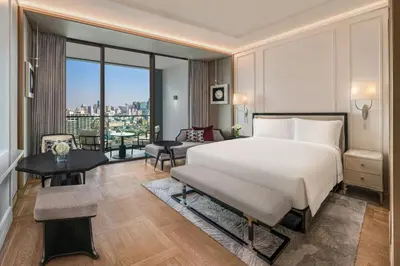 a bedroom with a large bed and a living room at The Ritz-Carlton, Bangkok in Bangkok