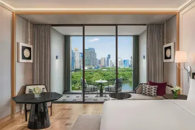 a bedroom with a bed and a living room with a large window at The Ritz-Carlton, Bangkok in Bangkok