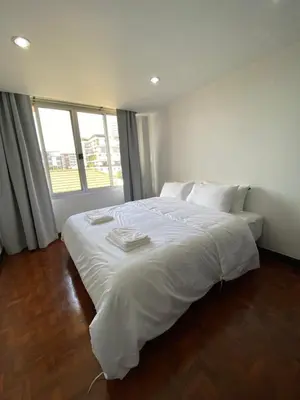 a white bed in a room with a large window at Phatana Court in Bangkok