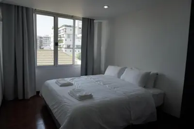 a white bed in a room with a window at Phatana Court in Bangkok